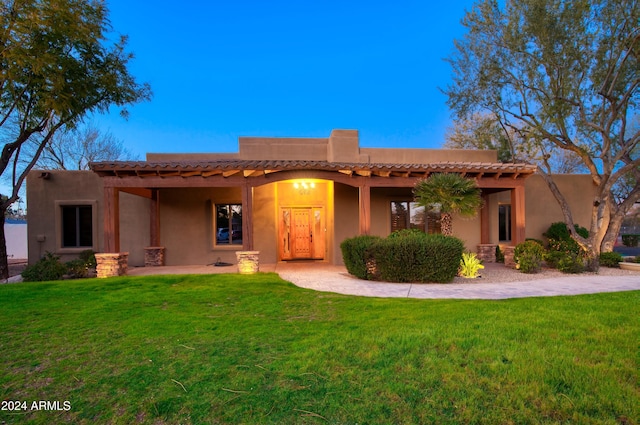 pueblo-style home featuring a front lawn