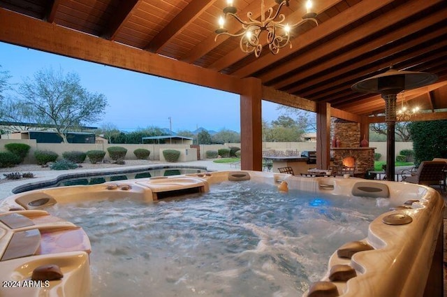 patio terrace at dusk with an outdoor stone fireplace and a hot tub