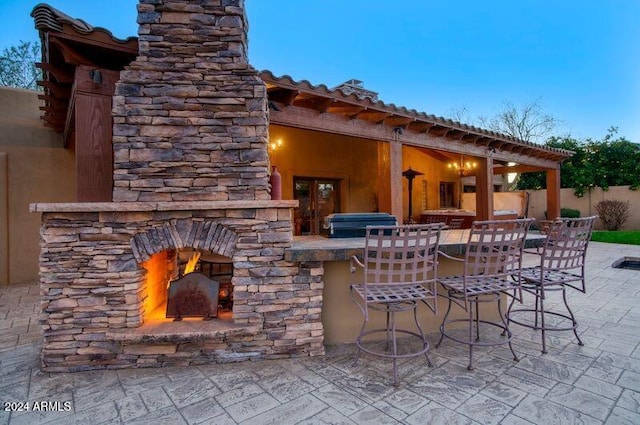 view of patio with an outdoor stone fireplace, outdoor dry bar, and fence