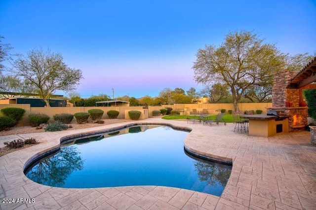 pool at dusk featuring a patio, a fenced in pool, a fenced backyard, grilling area, and outdoor dry bar