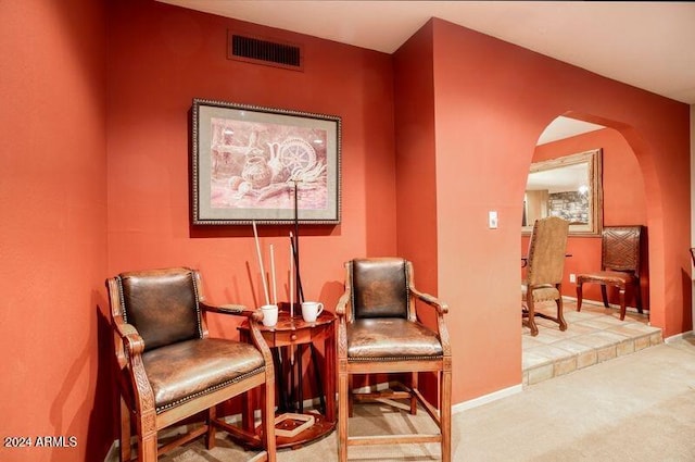 sitting room featuring arched walkways, visible vents, baseboards, and carpet