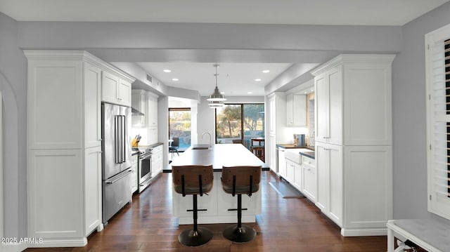 kitchen with a center island with sink, pendant lighting, white cabinetry, and stainless steel appliances