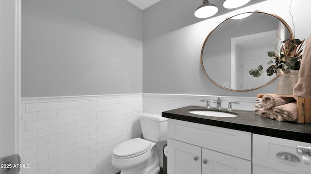 bathroom featuring vanity, toilet, and tile walls