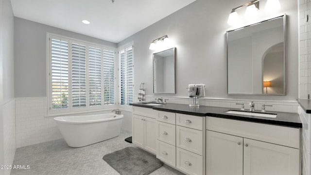 bathroom featuring tile patterned flooring, vanity, tile walls, and a tub