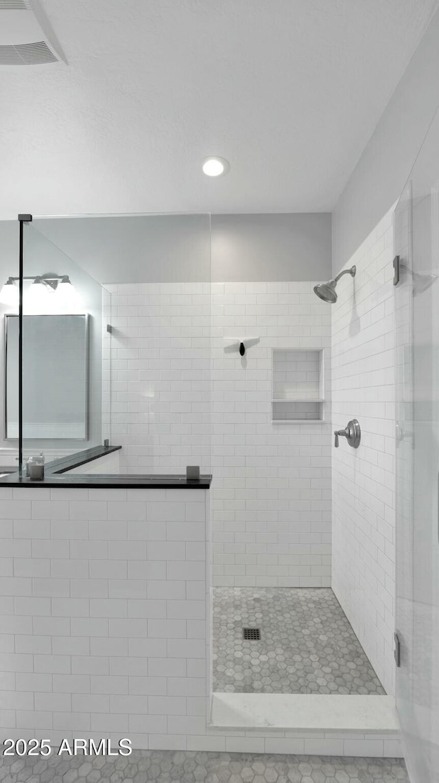 bathroom with tile patterned flooring and tiled shower