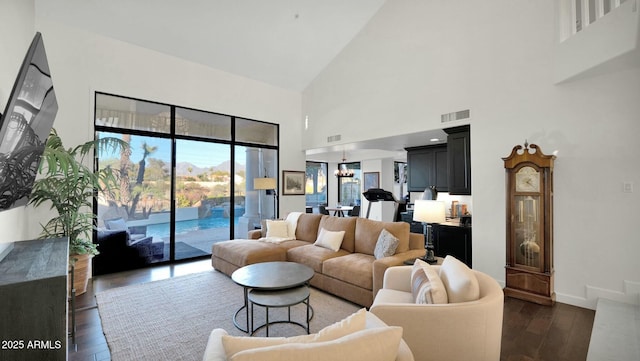 living room with dark wood-type flooring, high vaulted ceiling, and a chandelier