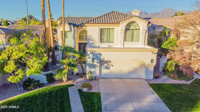 mediterranean / spanish-style home with a mountain view, a garage, and a front lawn