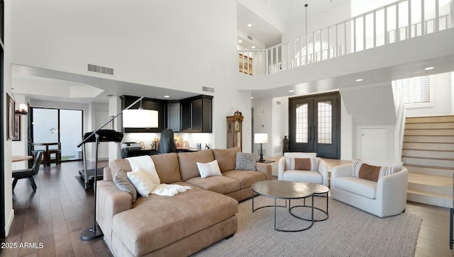 living room featuring a towering ceiling and dark wood-type flooring