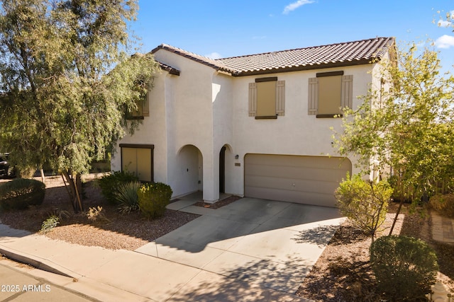 mediterranean / spanish-style home with stucco siding, an attached garage, a tile roof, and driveway