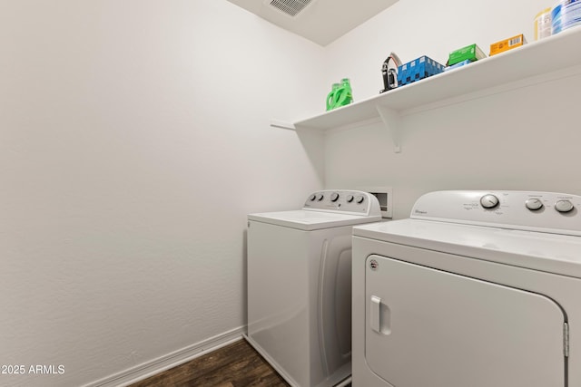 clothes washing area featuring visible vents, baseboards, laundry area, dark wood-style flooring, and washer and clothes dryer