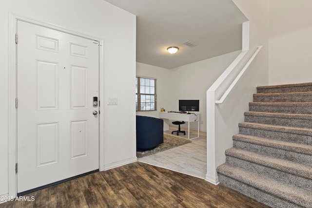 foyer entrance with stairs, wood finished floors, and visible vents