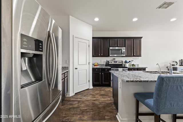 kitchen with visible vents, a sink, dark wood-style floors, stainless steel appliances, and light stone countertops