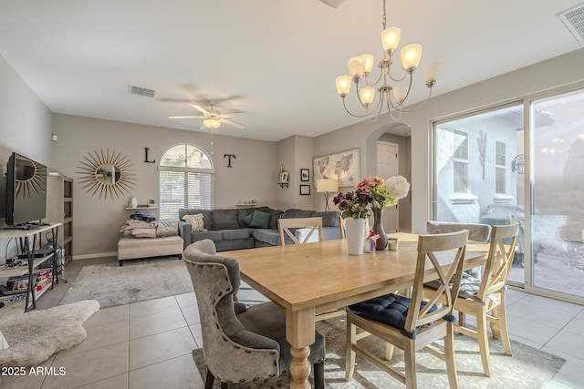 dining space with ceiling fan with notable chandelier and light tile patterned floors