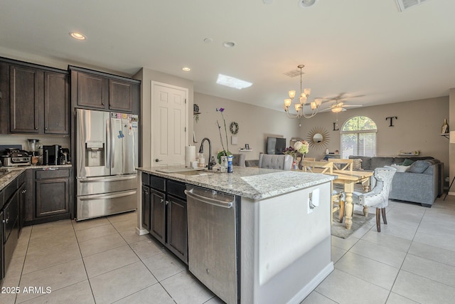 kitchen with sink, a center island with sink, light tile patterned floors, stainless steel appliances, and light stone countertops