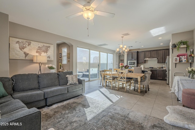 tiled living room featuring ceiling fan with notable chandelier