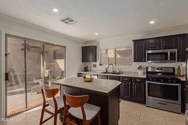 kitchen with light tile patterned floors, visible vents, a breakfast bar area, appliances with stainless steel finishes, and a sink