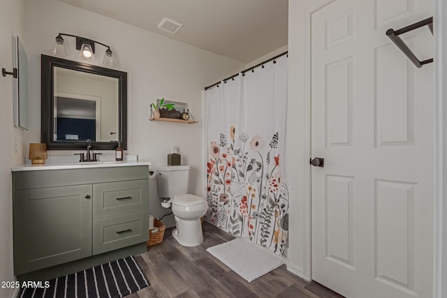 bathroom featuring visible vents, toilet, a shower with curtain, wood finished floors, and vanity