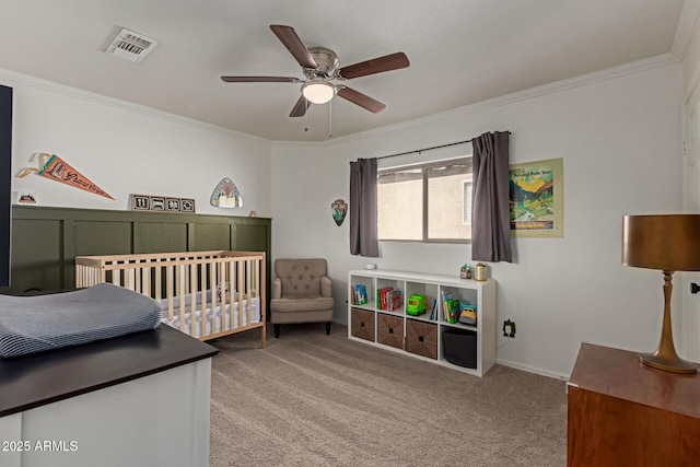 bedroom with carpet flooring, visible vents, a ceiling fan, ornamental molding, and a crib