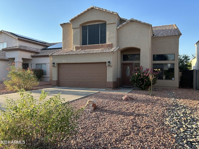 view of front of property featuring an attached garage, fence, a tile roof, stucco siding, and driveway