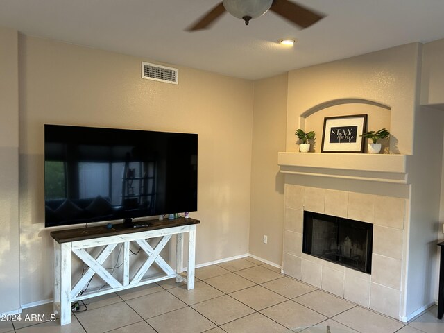 unfurnished living room with ceiling fan, light tile patterned floors, and a tiled fireplace