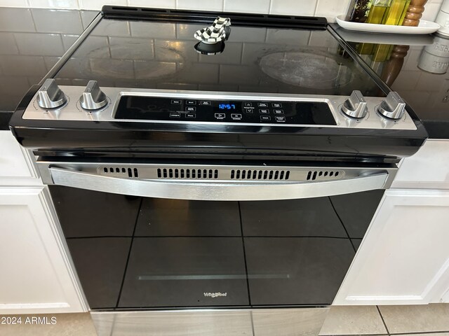 details featuring electric stove, backsplash, and white cabinetry