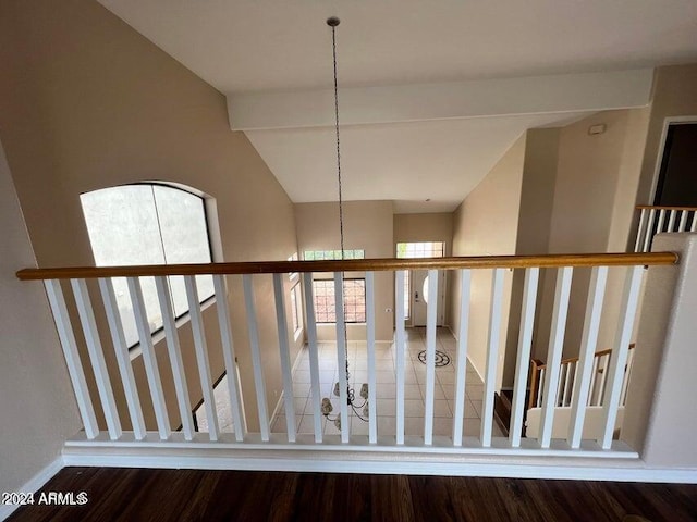 stairs with lofted ceiling, wood-type flooring, and a notable chandelier