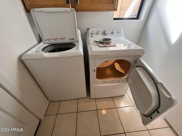 washroom featuring separate washer and dryer, cabinets, and light tile patterned floors