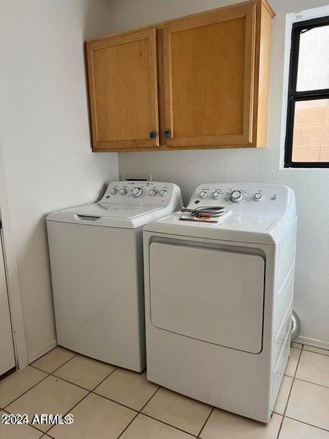 laundry room featuring cabinets, separate washer and dryer, and light tile patterned floors