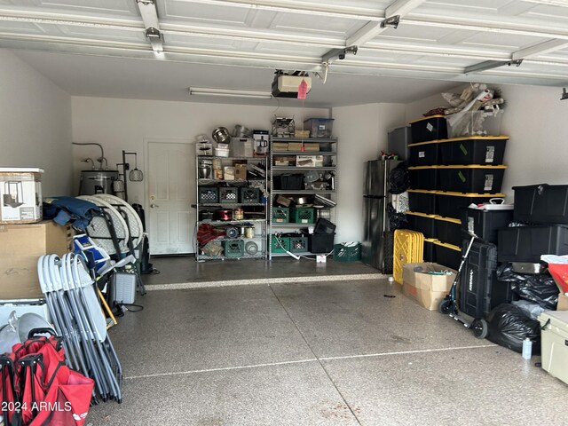 garage featuring electric water heater, black refrigerator, and a garage door opener