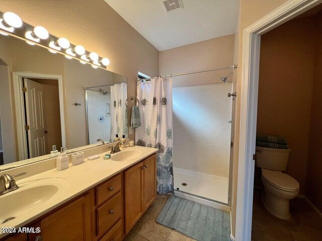 bathroom with tile patterned flooring, vanity, toilet, and walk in shower