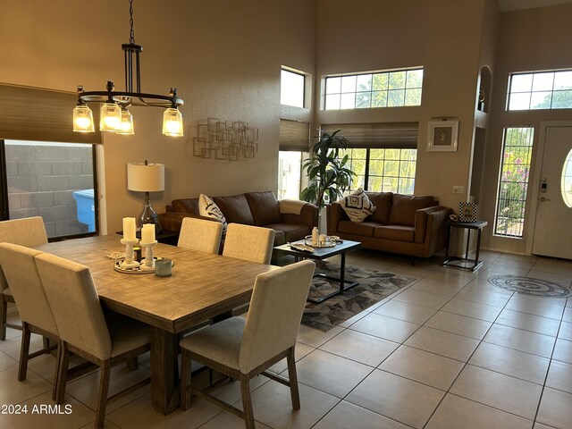 dining room with a towering ceiling, a chandelier, and light tile patterned flooring