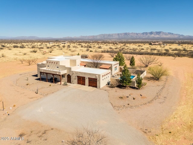 southwest-style home with a mountain view, a garage, view of desert, and dirt driveway