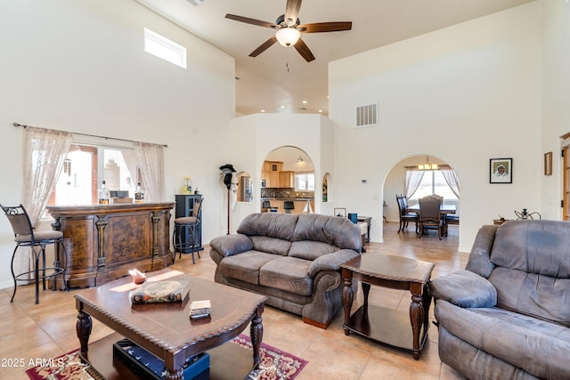 living room featuring ceiling fan with notable chandelier, light tile patterned floors, arched walkways, and visible vents