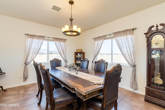 tiled dining room featuring a wealth of natural light, a notable chandelier, baseboards, and visible vents