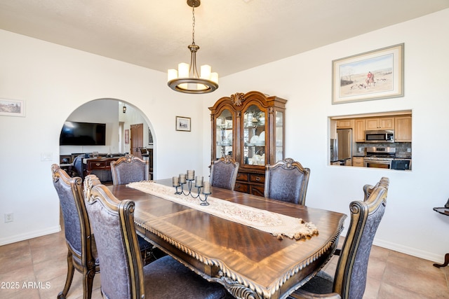 dining space featuring a notable chandelier, baseboards, and arched walkways