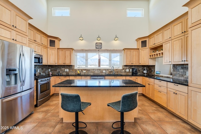 kitchen featuring light brown cabinetry, stainless steel appliances, and a kitchen bar