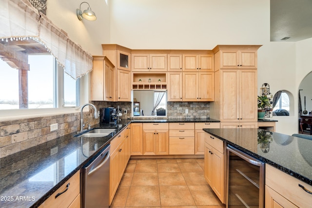 kitchen with light brown cabinets, wine cooler, light tile patterned floors, stainless steel dishwasher, and a sink