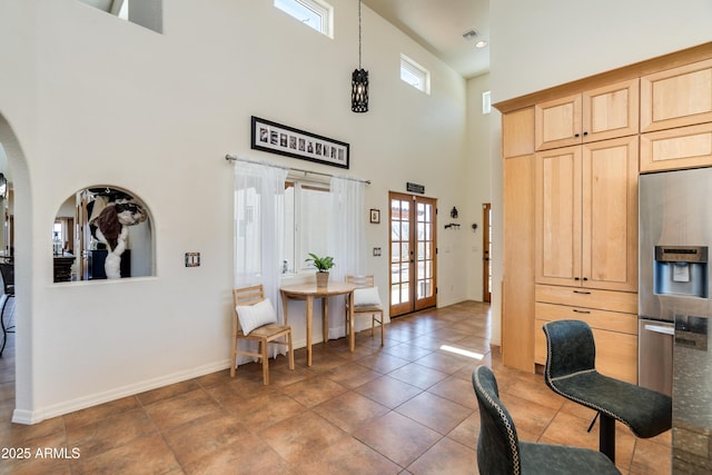 interior space with baseboards, a high ceiling, arched walkways, french doors, and tile patterned floors