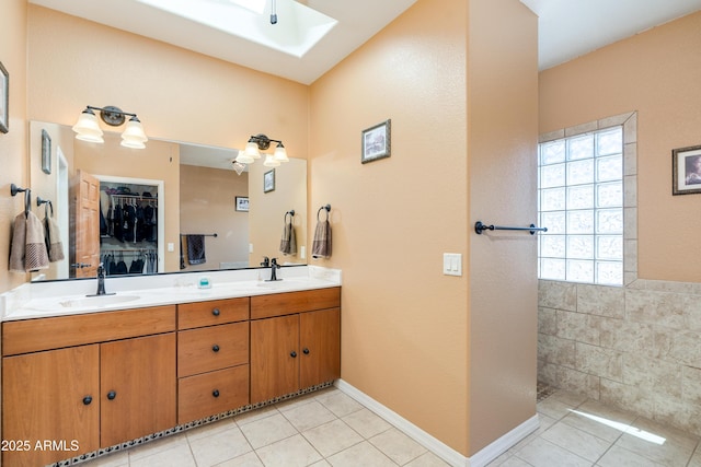 full bathroom featuring a sink, a skylight, double vanity, and tile patterned floors