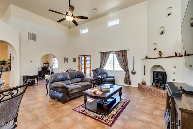 living area featuring arched walkways, visible vents, ceiling fan, and light tile patterned flooring