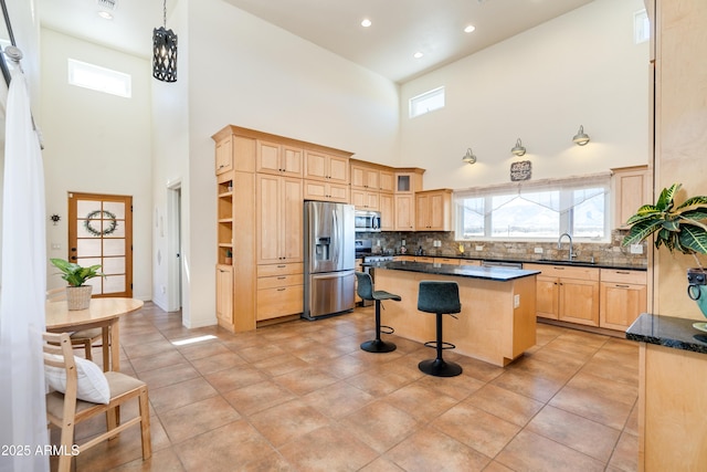 kitchen with a kitchen island, light brown cabinetry, a breakfast bar, stainless steel appliances, and a sink