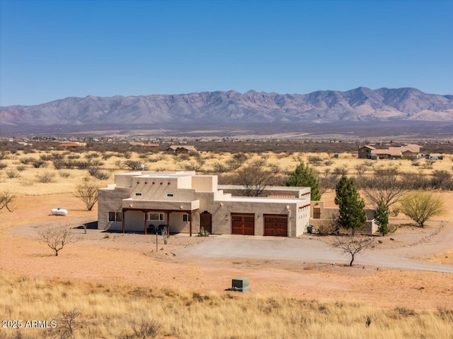 view of front of property with stucco siding, driveway, an attached garage, and a mountain view