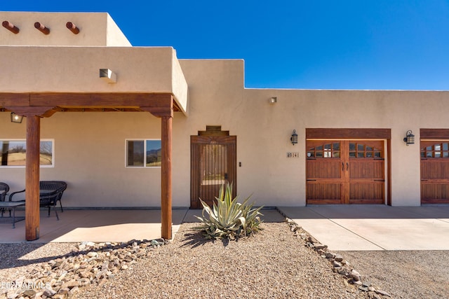 doorway to property featuring concrete driveway, a gate, and stucco siding