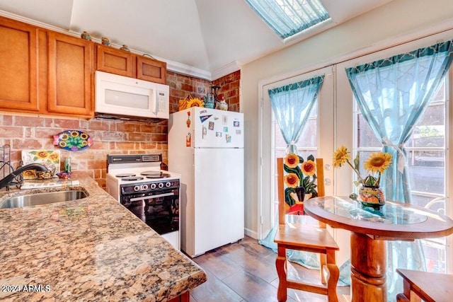 kitchen featuring white appliances, a healthy amount of sunlight, light stone counters, and lofted ceiling