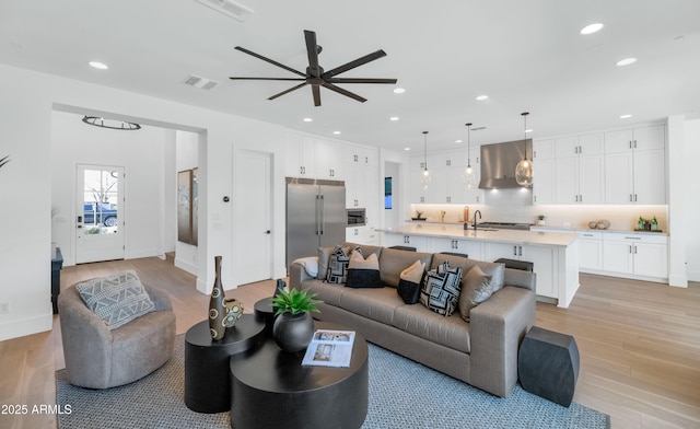 living room featuring ceiling fan, light wood-type flooring, and sink