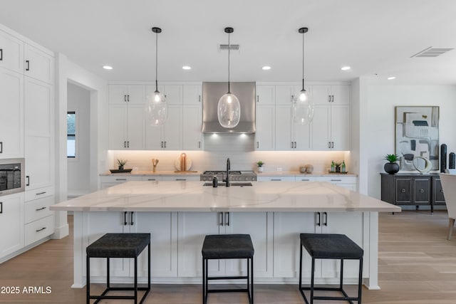 kitchen with a breakfast bar, black microwave, a spacious island, and white cabinetry