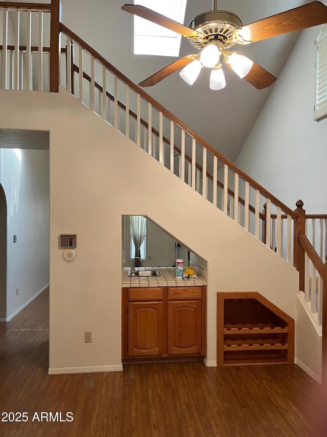 6223 N 12th St Unit 1, Phoenix, AZ 85014 - unfurnished living room with high vaulted ceiling, a ceiling fan, dark wood-style floors, stairs, and arched walkways