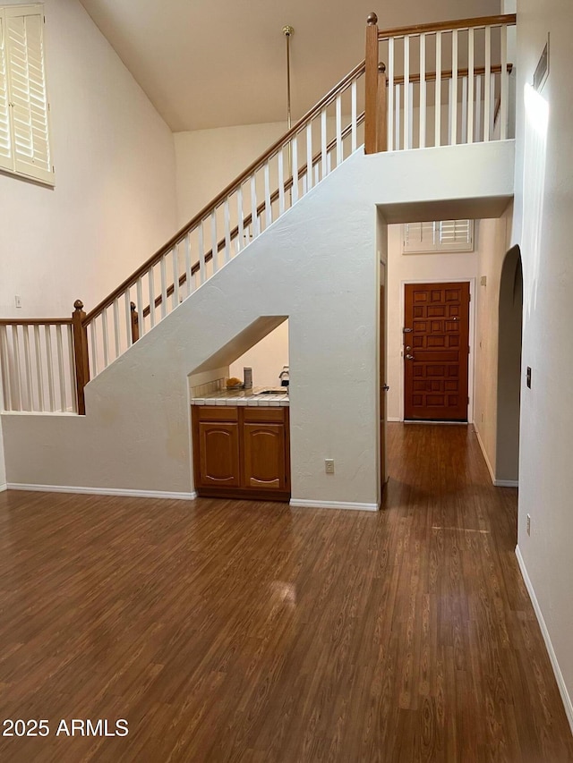 6223 N 12th St Unit 1, Phoenix, AZ 85014 - unfurnished living room with a towering ceiling, dark wood-type flooring, arched walkways, and stairway