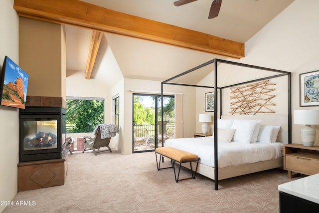 carpeted bedroom with access to exterior, a tiled fireplace, and lofted ceiling with beams