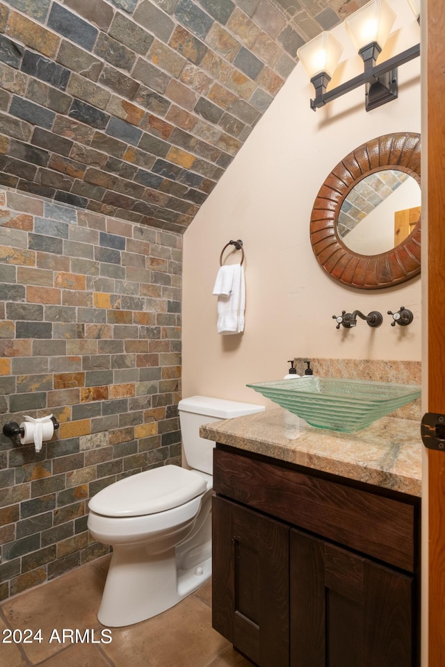 bathroom featuring lofted ceiling, brick ceiling, vanity, and toilet